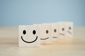 Mental health assessment, Emotion, Think positive, Satisfaction survey, service review and feedback concept. Wood cube with smile stand in front of sad face. Positive to negative facial expressions.
