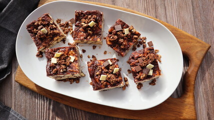 Lazy cake or mosaic cake with granola and chocolate . Homemade no bake chocolate biscuit cake on a wooden table