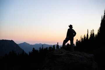 Silhouette image of a man standing on rocks at sunset. Paradise. Mt Rainier National Park. Washington State.