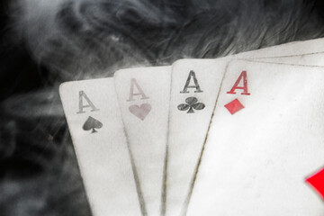 Four aces of playing cards close-up are shrouded in thick smoke	
