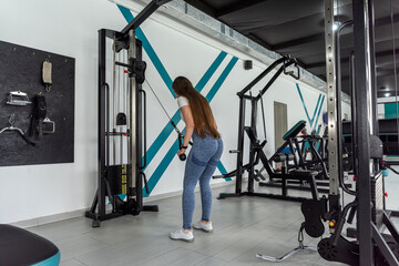  Attractive caucasian woman in sportswear doing exercise on exercise-machine in the gym