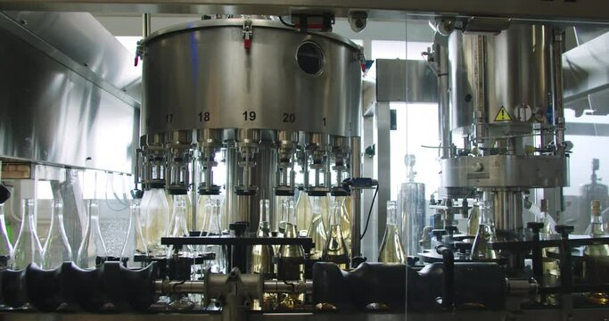 Amazing wide in slow motion shot of machinery that fills white wine bottles inside a wine factory in Burgos, Spain
