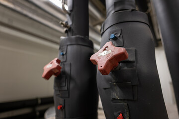 Rotary manual red valves on insulated pipe.