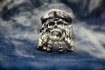 A ring in the form of a pirate skull shrouded in smoke on a black background	

