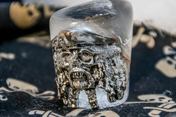 Frozen ring in the form of a pirate's skull close-up stands on a mat with pirate symbols	
