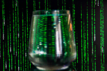 The letters, numbers and hieroglyphs of the matrix fall on a black background in front of a glass...