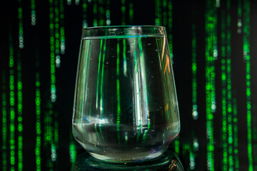 A transparent glass of water stands against the background of falling green numbers and letters.	
