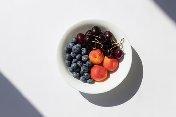 Organic ripe berries and fruits in the white bowl. Close up. Copy space