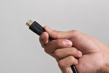 Hand holding HDMI cable connector on white background