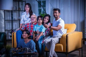 Indian big family watching television at home on sofa