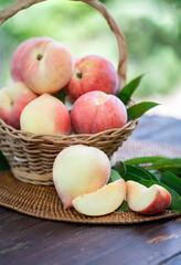 Fresh Peach with sliced on the wooden table over blurred greenery background, Fresh peach on wooden basket in wooden Background.