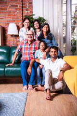 Happy Indian asian family consists of grandparents, parents and kids posing for photo sitting on...