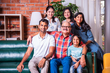 Happy Indian asian family consists of grandparents, parents and kids posing for photo sitting on...