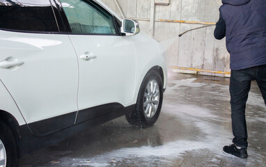 Closeup of male driver washing his car with contactless high pressure water jet in self service car...