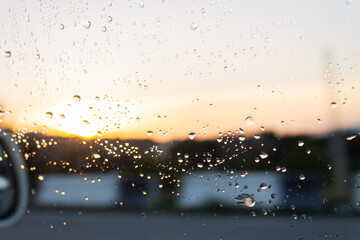 Water drops on a window glass after the rain. The sky with clouds and sun on background