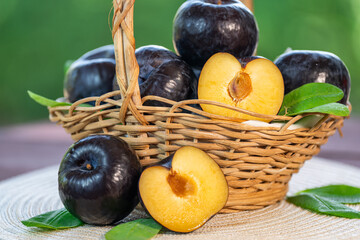 Fresh Black Plum fruit in Bamboo basket on wooden table in garden, Fresh Black Plum with slices on...