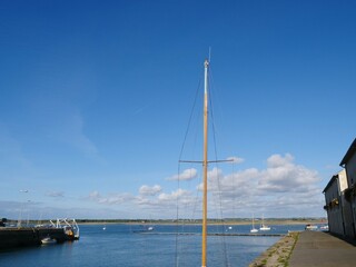 Le Croisic, France, mast from a leisure sail boat on the quay, the background is the entrance area of the harbor , leisure boats and signs regulating shipping traffic.