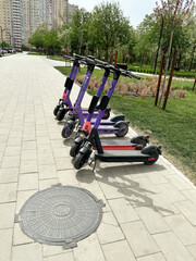 electric scooters stand on the sidewalk in a city park