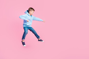 Full body profile photo of active little boy jump hit fight empty space isolated on pink color background