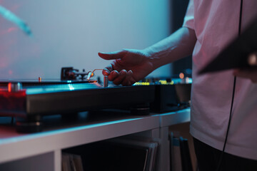 Close-up of a DJ's hand on a turntable, playing music at a vibrant party.