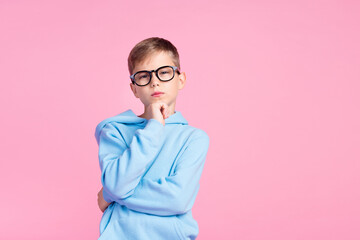 Portrait of minded intelligent schoolchild hand touch chin contemplate empty space isolated on pink color background