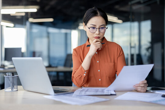 Focused businesswoman reviewing documents in modern office