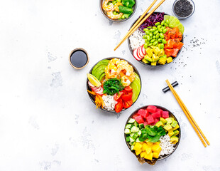 Poke bowls with vegetables and seafood in assortment, white table background, top view