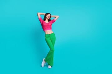 Full size photo of adorable gorgeous girl wear pink knit top green trousers hold arms behind head...
