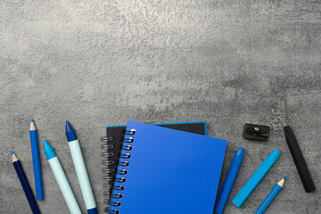 Notebook and colored crayons on stone texture background. Work desk space