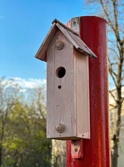 A wooden birdhouse on a pole in the park in summer. An outdoor bird house . 