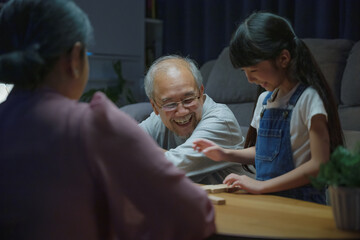 Happy grandparents Asian family enjoy playing toy block with little daughter together in home...