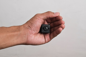 Hand holding a spy camera isolated on white background. Black security camera, Mini spy camera