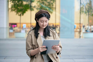 Stylish Young Woman Browsing on Tablet in City