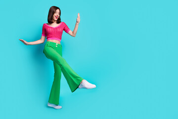 Full size photo of positive girl wear pink knit top green trousers dancing look empty space show...