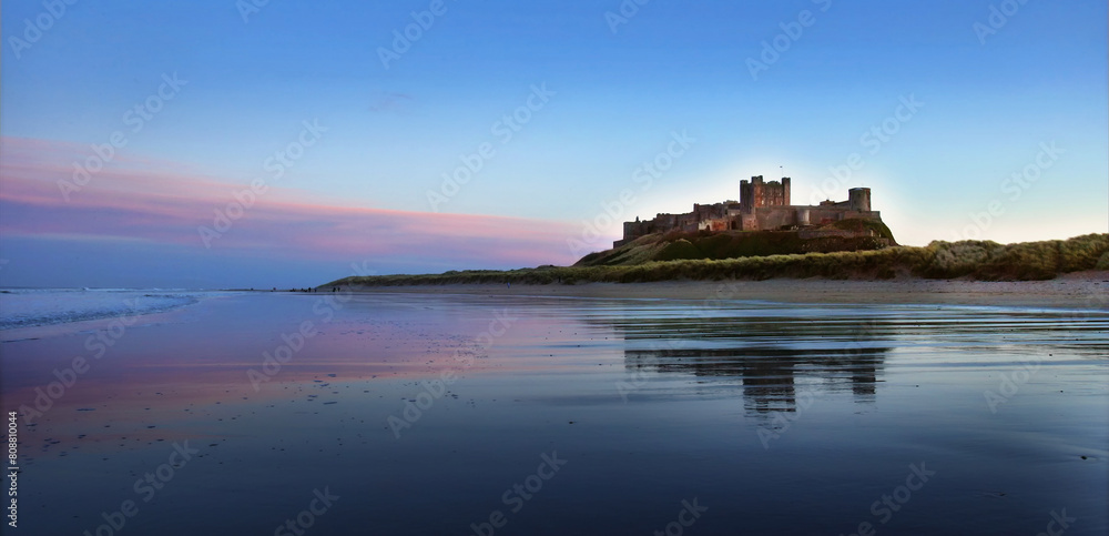 Wall mural sunset on bamburgh castle, on the northeast coast of england, by the village of bamburgh in northumb