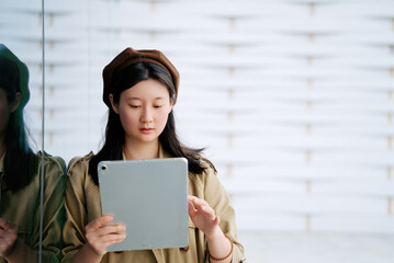 Stylish Young Woman Engrossed in Her Tablet Outdoors