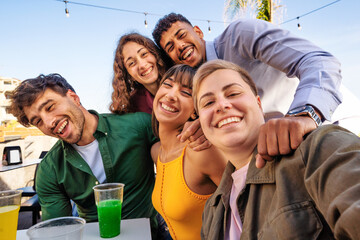 Group of diverse friends - laughing and enjoying drinks at a beach gathering, showing joy and togetherness in a casual outdoor setting.