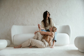 Conception of care. Woman leaning on the legs. Two happy young female best friends are indoors