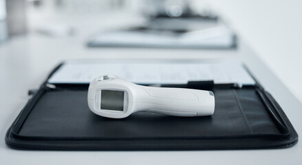 Medical, digital and thermometer gun in office of hospital with clipboard for data, information and...