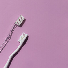 Plastic toothbrushes on the bright violet background. Top view. Copy space
