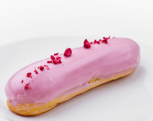 Pink iced eclair on white plate