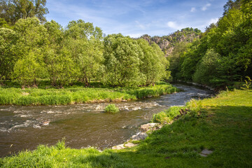 Spring landscape with river and rocky hill under blue sky