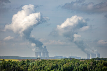 Spring or summer landscape with forest and nuclear power plant under blue cloudy sky