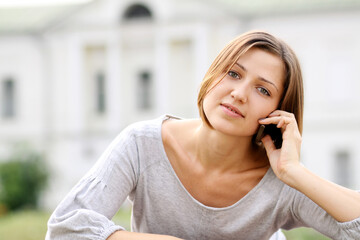 Young happy woman calling by phone on the street