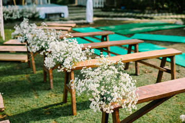 Beautifully adorned wooden chairs embellished with wedding floral decorations, adding charm and...