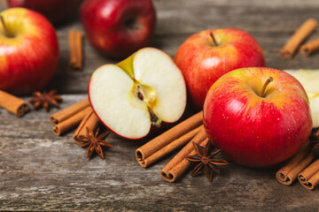 Apples with cinnamon on a textured wooden background. Fragrant red spiced apples with cinnamon sticks and star anise. Apple slices with spicy spices. Place for text. Copy space. Harvesting. Fruits. 