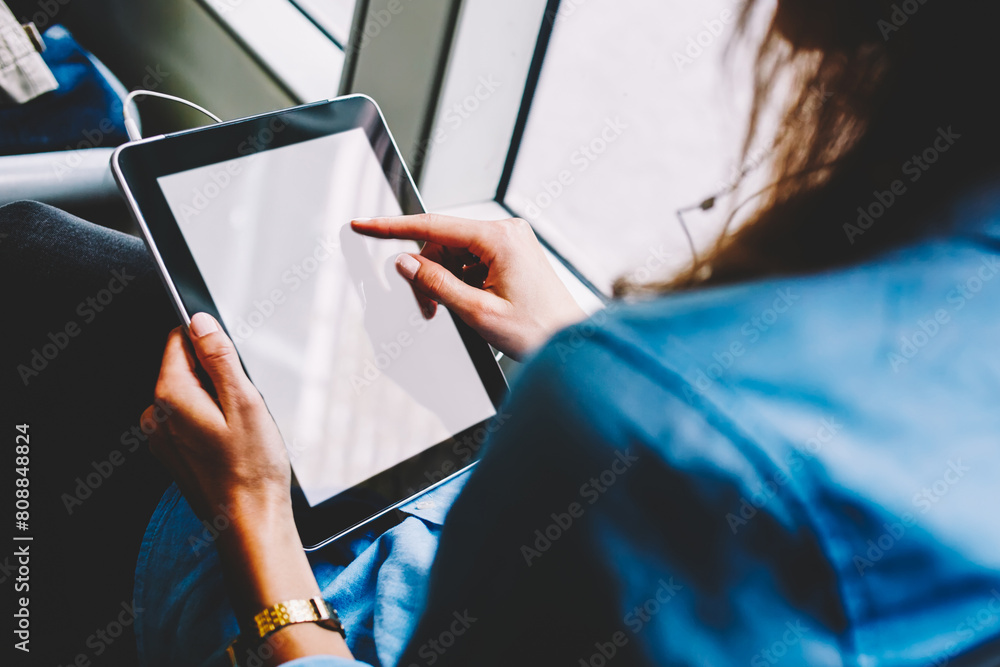 Poster cropped image of woman tap on touchpad screen using online app for watching video sitting inside bus