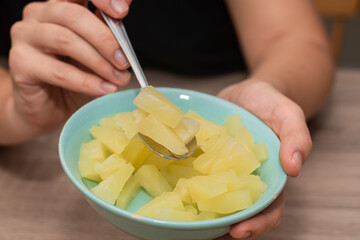 Serving Bowl of Diced Pineapple. Close-up view of a person's hands holding a bowl of freshly diced...