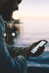 Cropped image of positive man smiling while reading message on mobile phone with mock up screen...