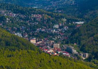 Obraz premium Travel to Romania Carpathian mountain side. Aerial drone photo with Sinaia mountain resort located in Prahova Valley (Valea Prahovei in Romania) at the bottom of Bucegi mountains. 